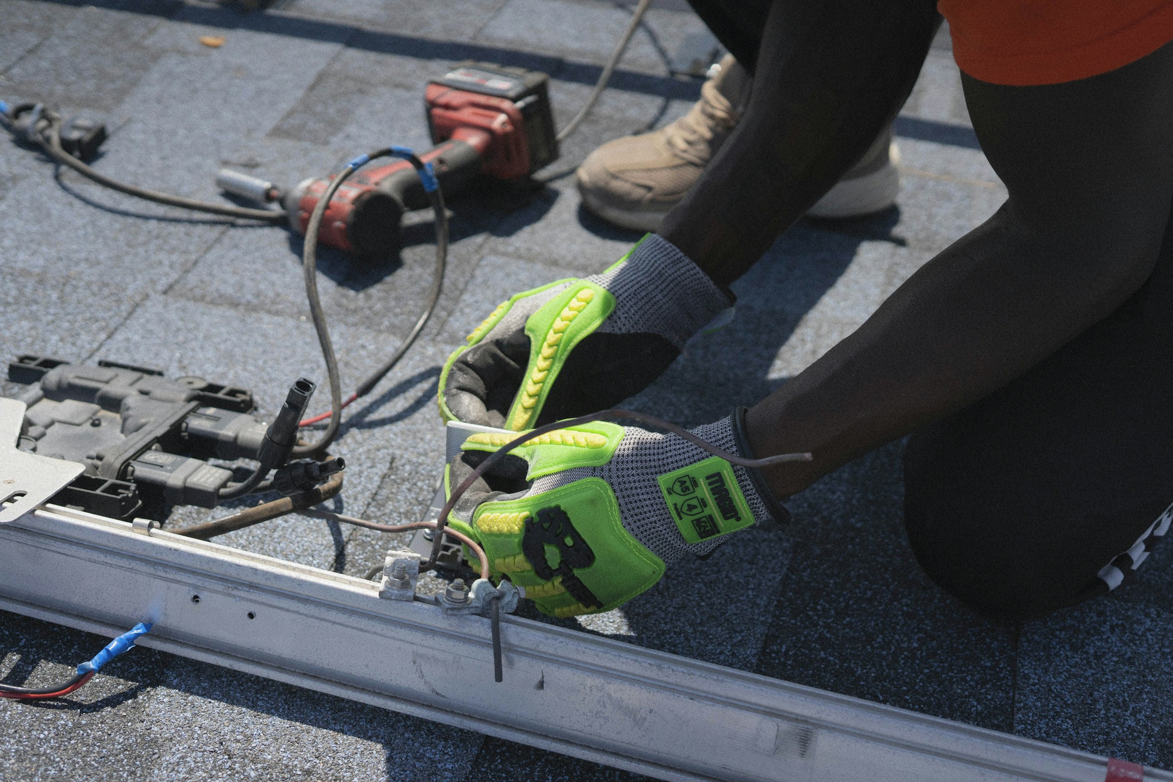 Gloved hands drilling a mounting rail into a concrete roof
