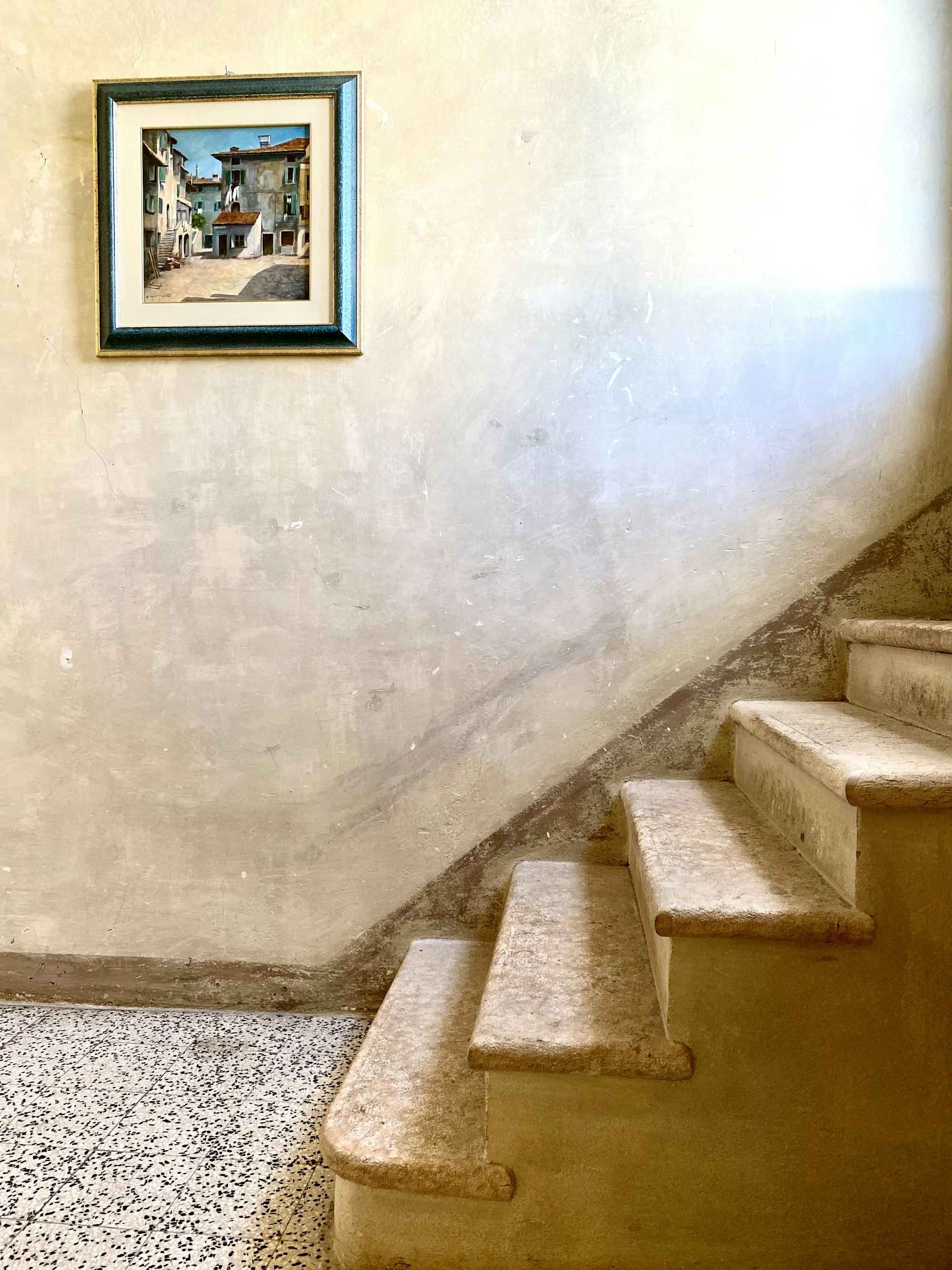 A plain plastered staircase with one small framed painting