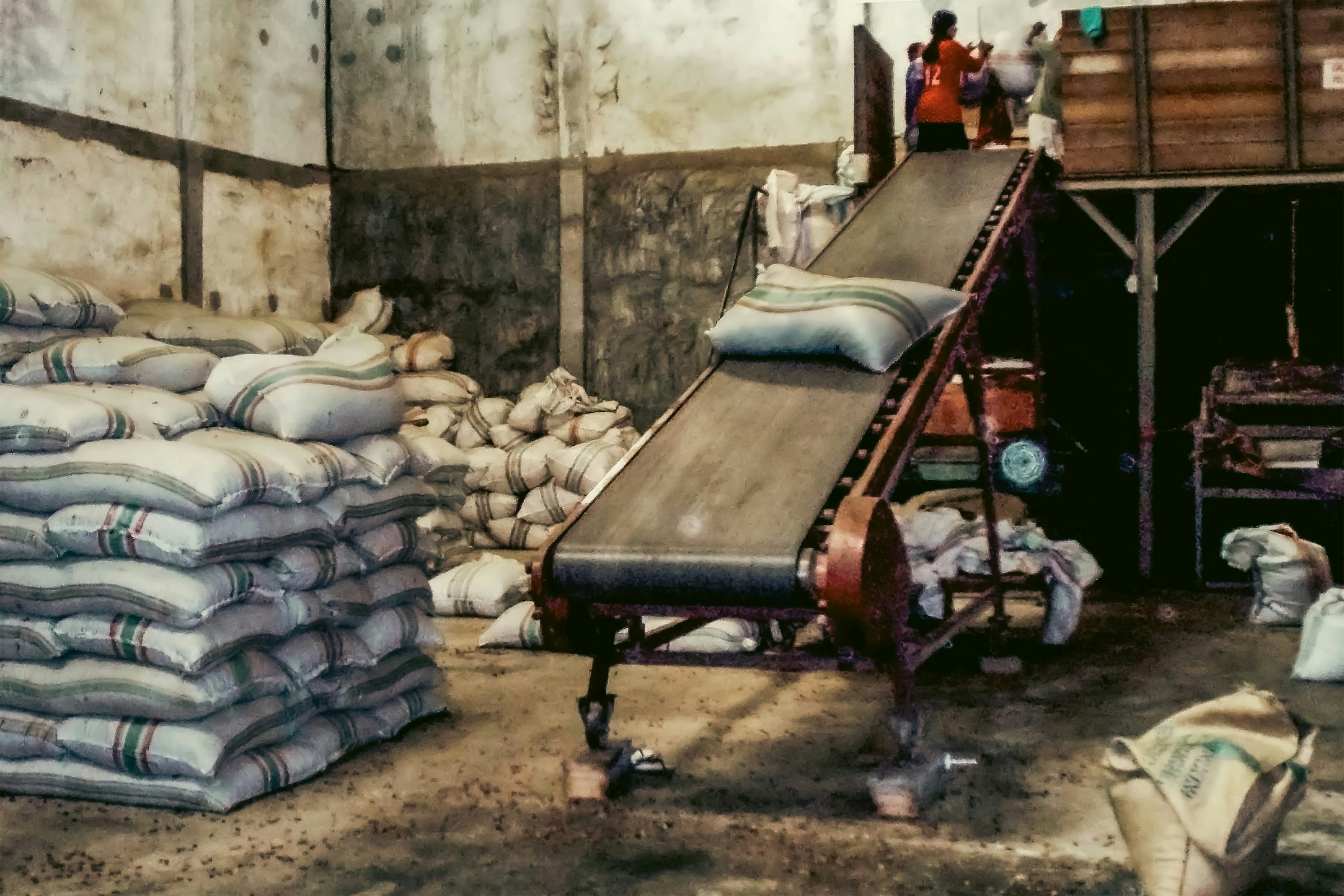 Stacked jute sacks beside a conveyor in a warehouse